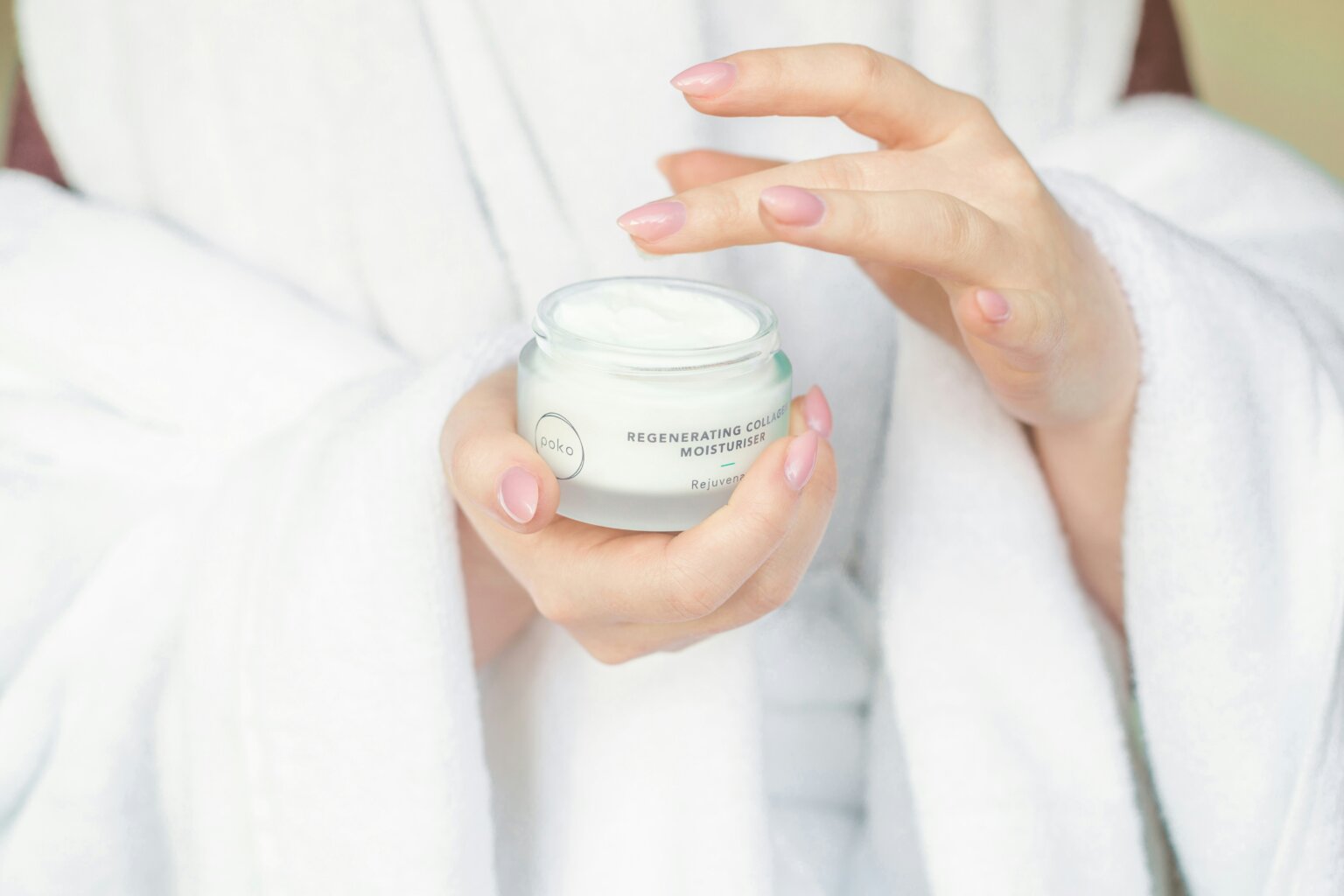a girl holding a skincare product wearing a robe